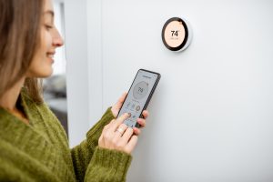 Woman adjusting a smart thermostat through her phone