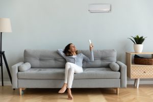 Woman sitting on couch next to a wall-mounted ductless unit