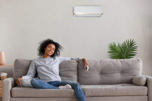 Woman sitting on couch next to a wall-mounted ductless unit
