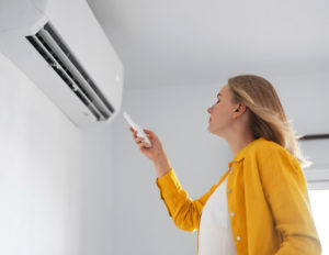 Woman stands in front of the air conditioner.