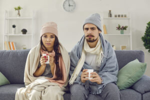 cold couple in winter wear and blankets on couch