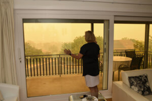 woman looks out of window at wildfire haze
