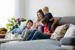 family sits together on couch reading books
